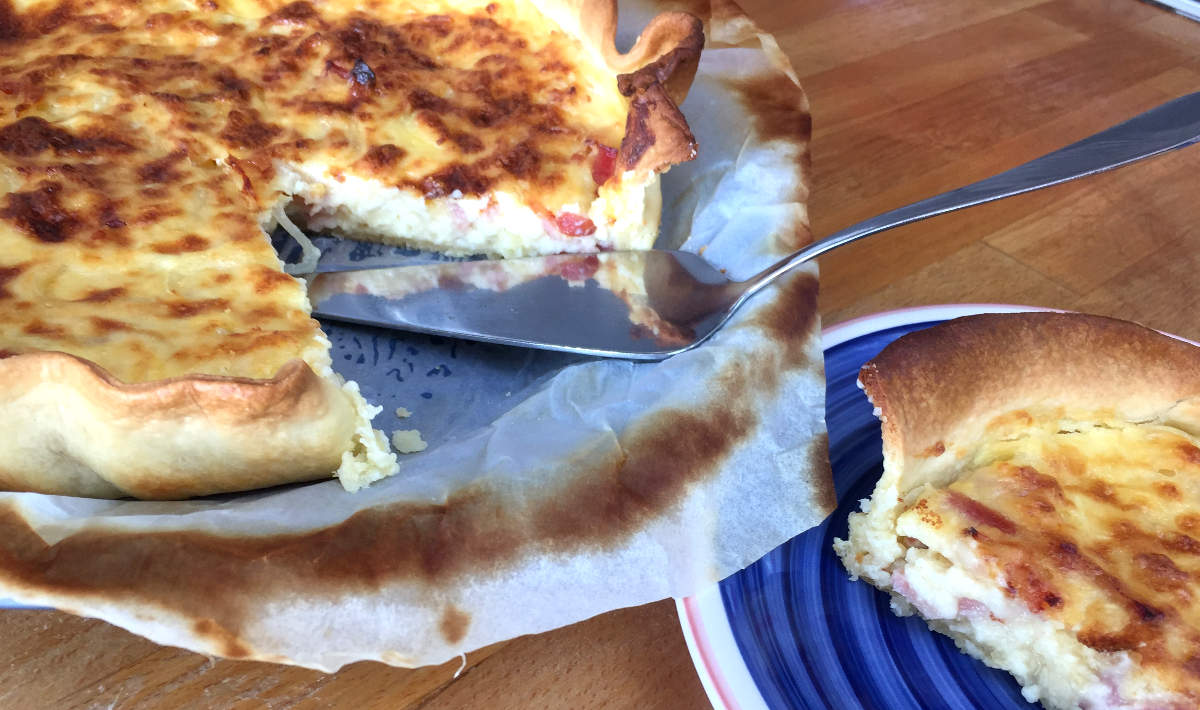 Quiche de Bacon e Cebola fácil e Irresistível servida com uma fatia extra ao lado.